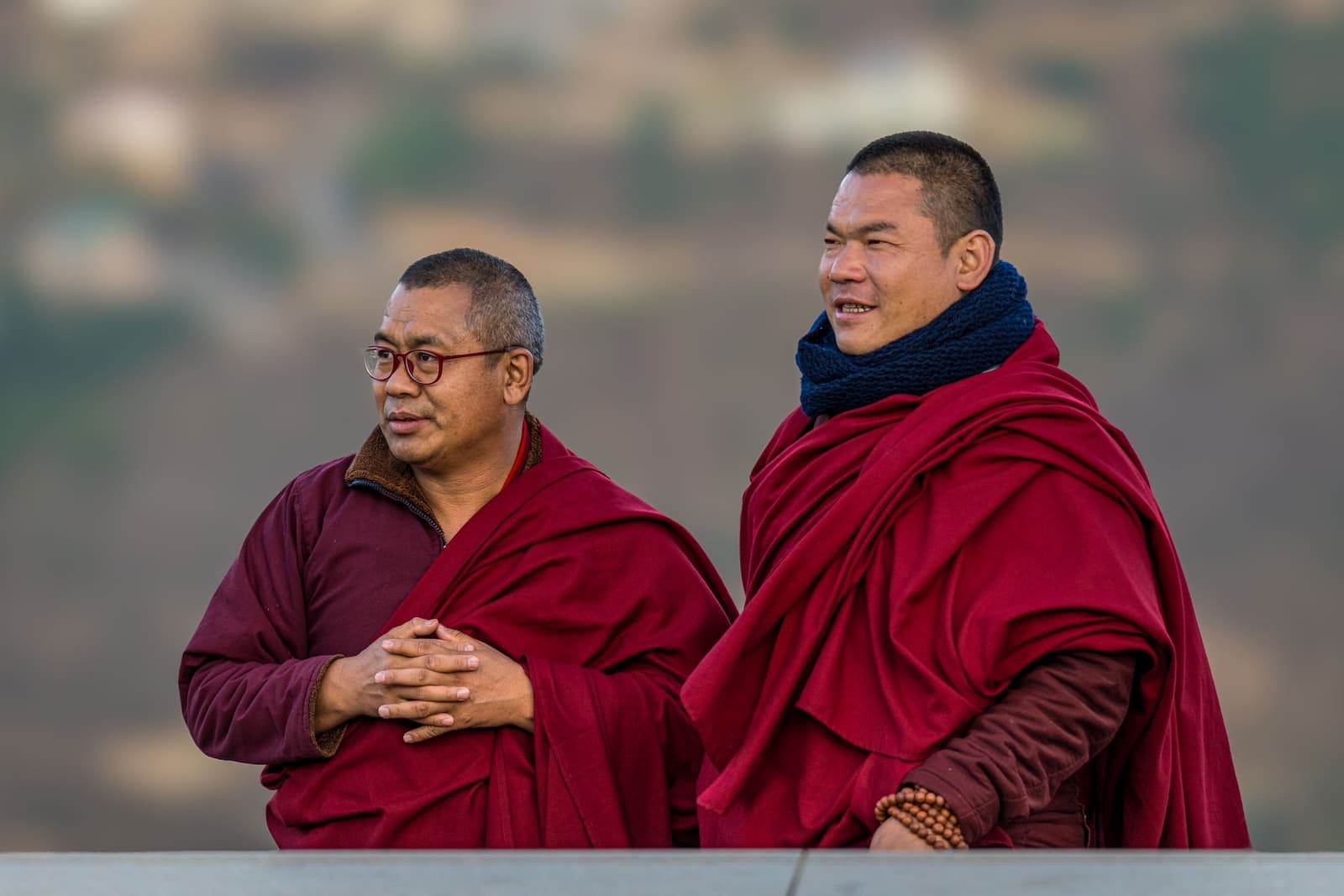 Two Bhutanese monks in maroon robes sharing a laugh