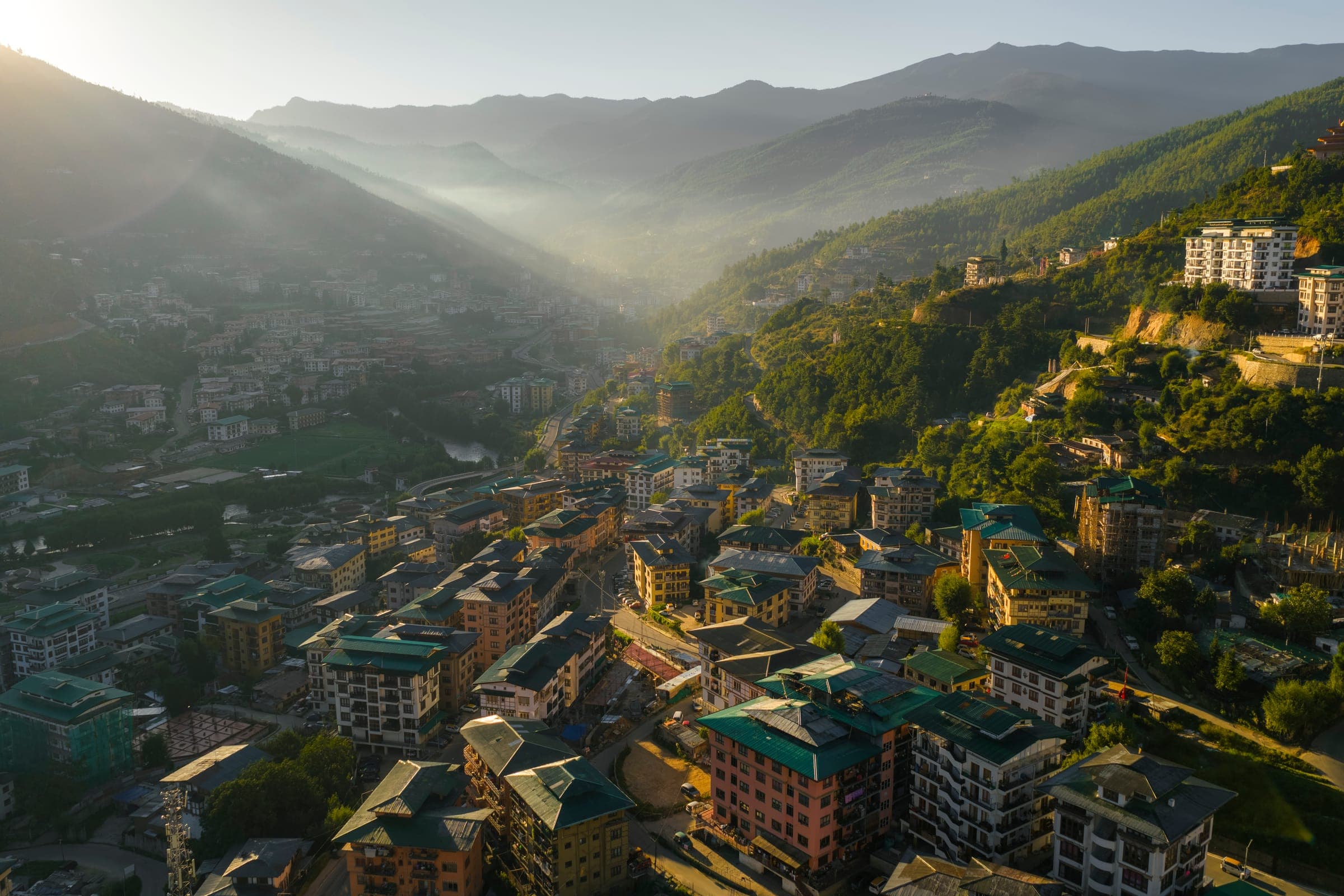 Morning light over a Bhutanese town in a forested valley