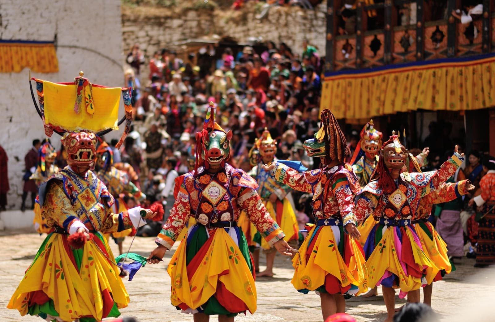 Masked cham dancers in brocade costumes at a Bhutanese tshechu