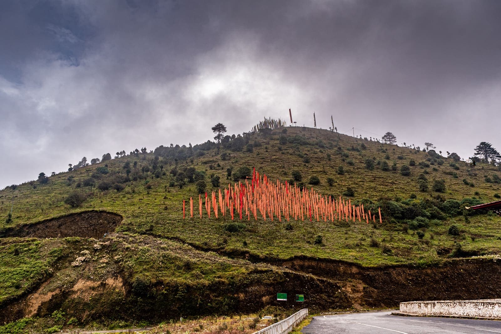 A road winding past a hill of prayer flags