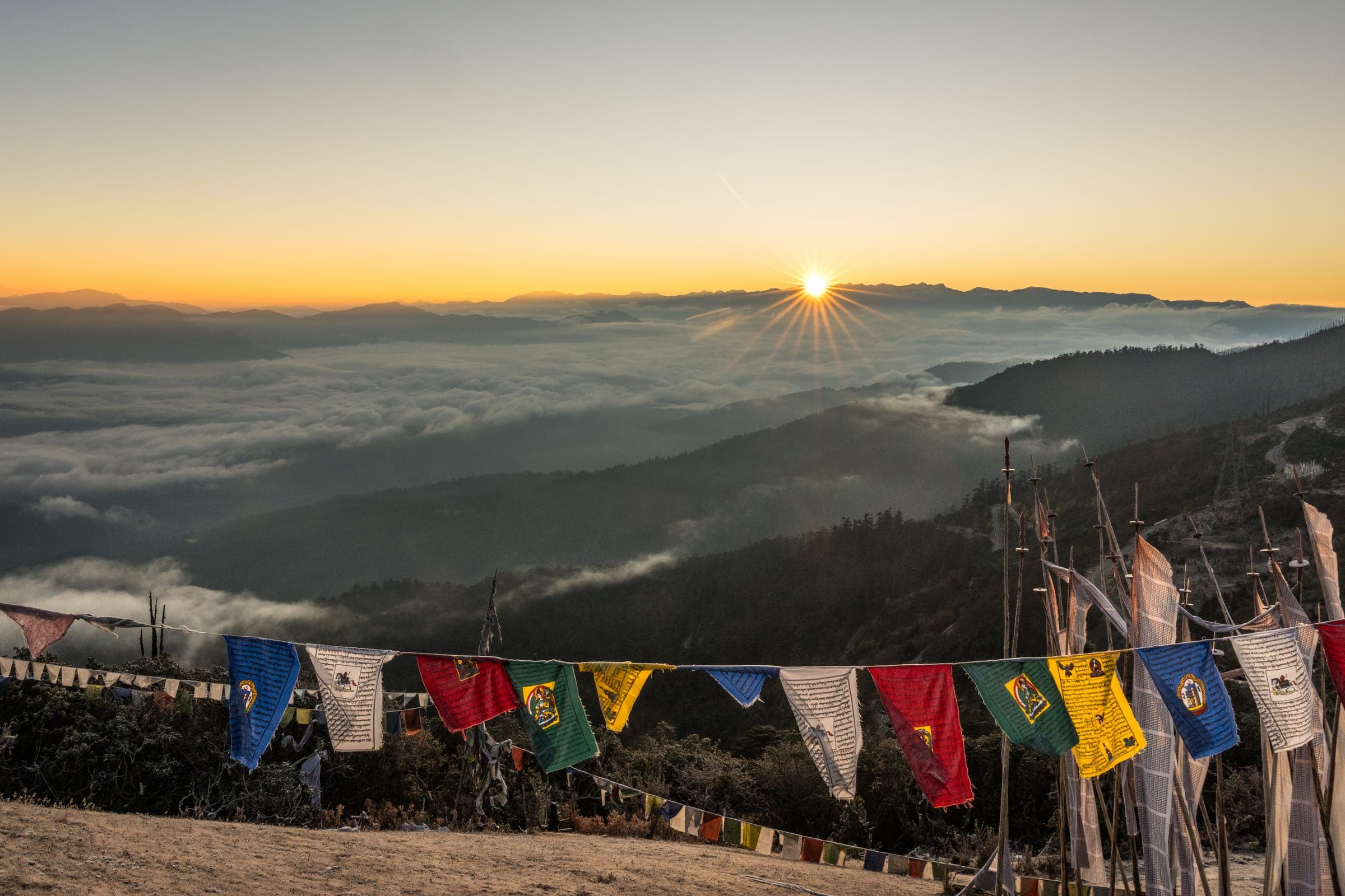 Sunrise over a sea of cloud with prayer flags in the foreground
