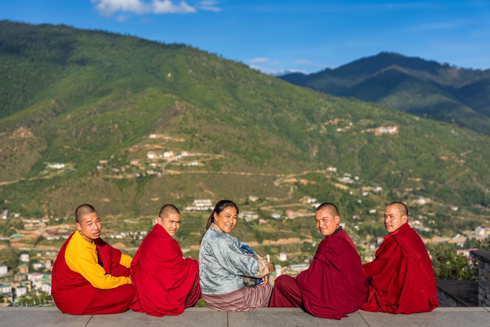Bhutanese monks and travellers sitting together in the sun