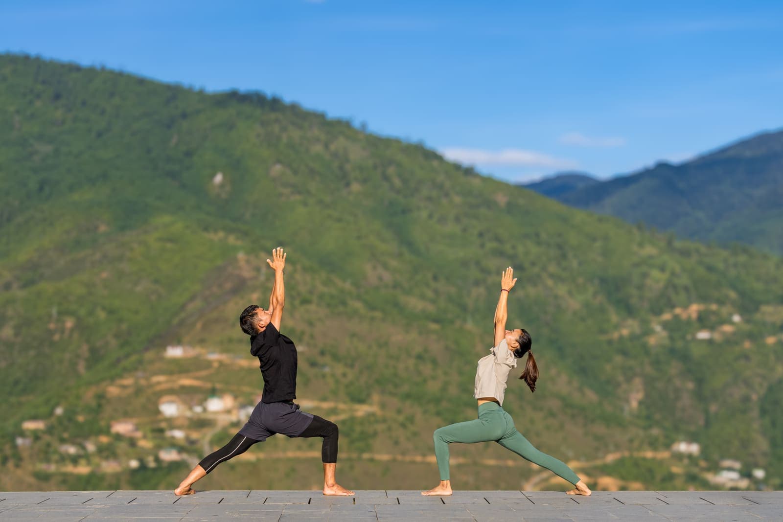 Two people practising yoga on a hillside above Thimphu