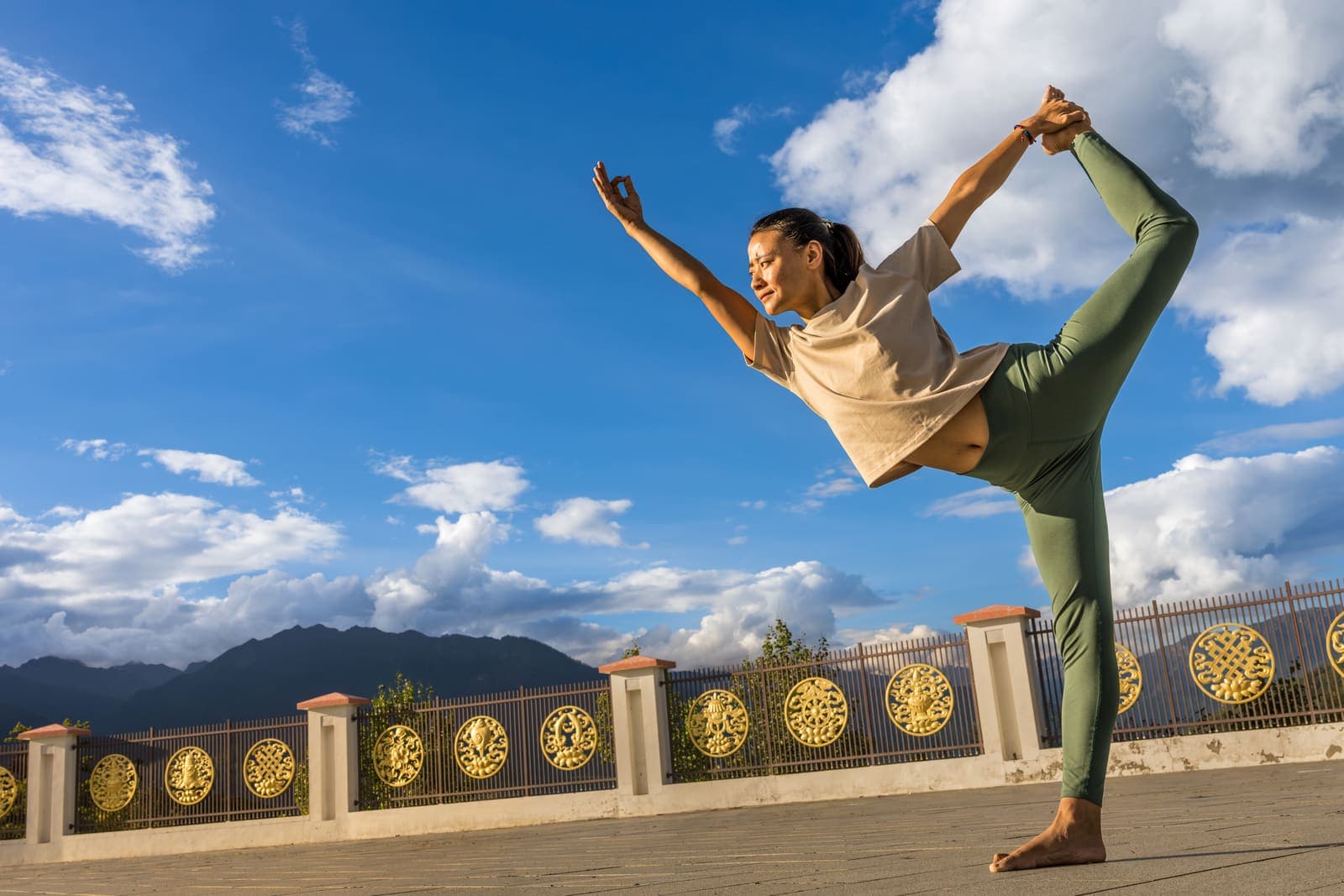 A woman practising yoga above Thimphu with prayer wheels behind